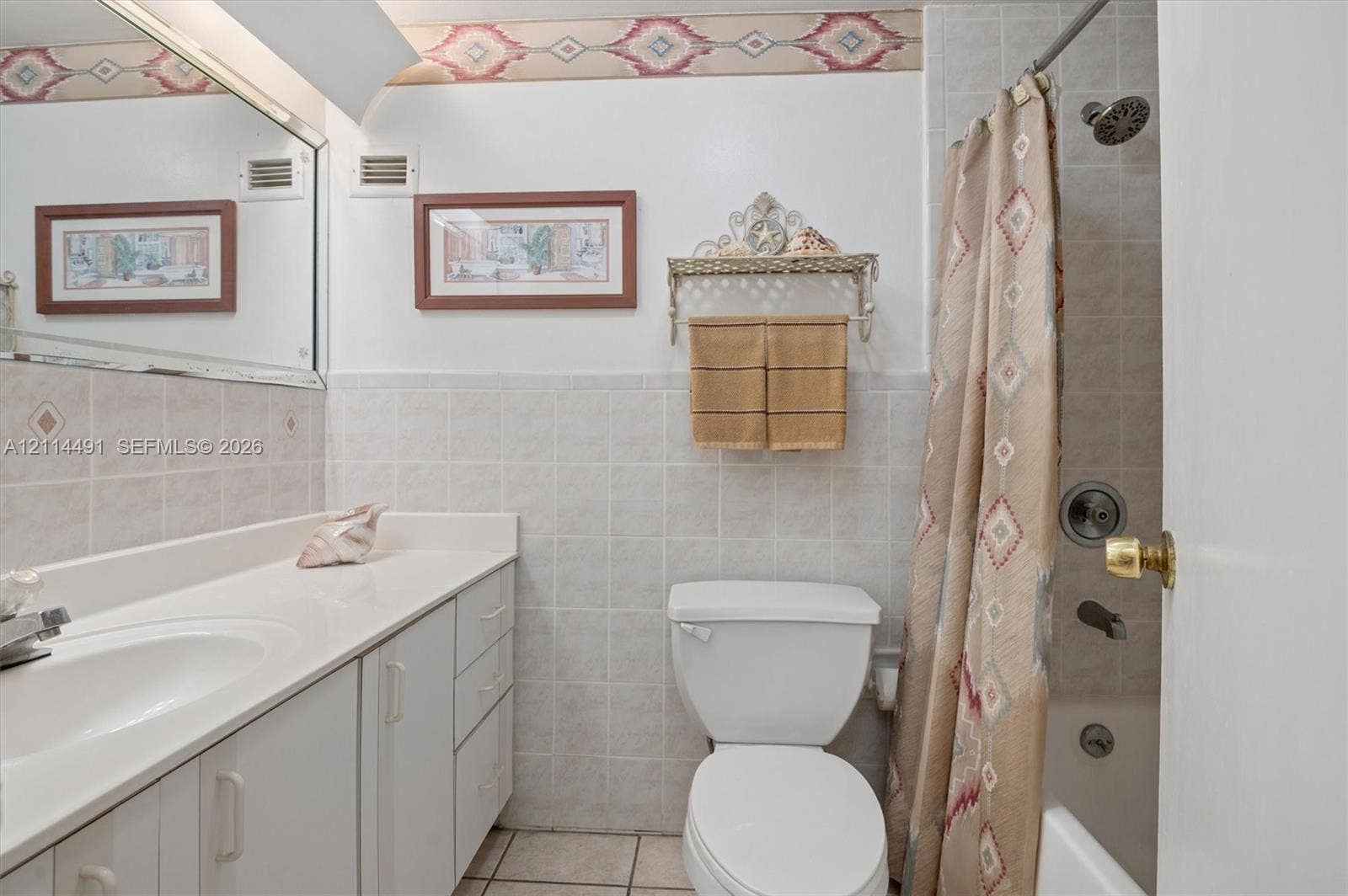 3505 S Ocean Drive, #217, Hollywood, FL 33019 Bathroom featuring a white vanity with an integrated basin, wall-to-wall mirror, ceramic tile wainscoting, and a shower-tub combination with chrome fixtures