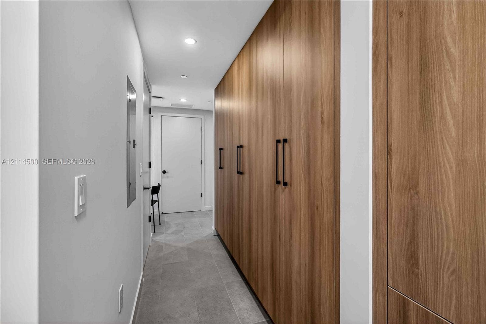 121 NE 5th Street, #712B, Miami, FL 33132 Full-height wall cabinetry with wood-finish paneling, matte black hardware, recessed ceiling lighting, and large-format tile flooring