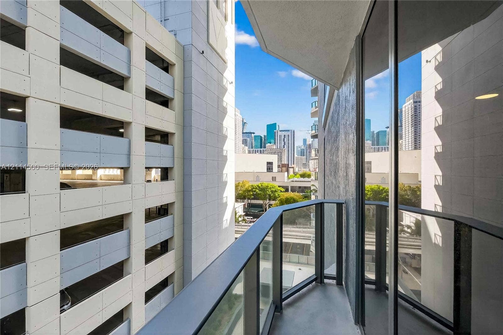 121 NE 5th Street, #712B, Miami, FL 33132 Covered balcony with black metal railings and glass panels, featuring urban skyline surroundings