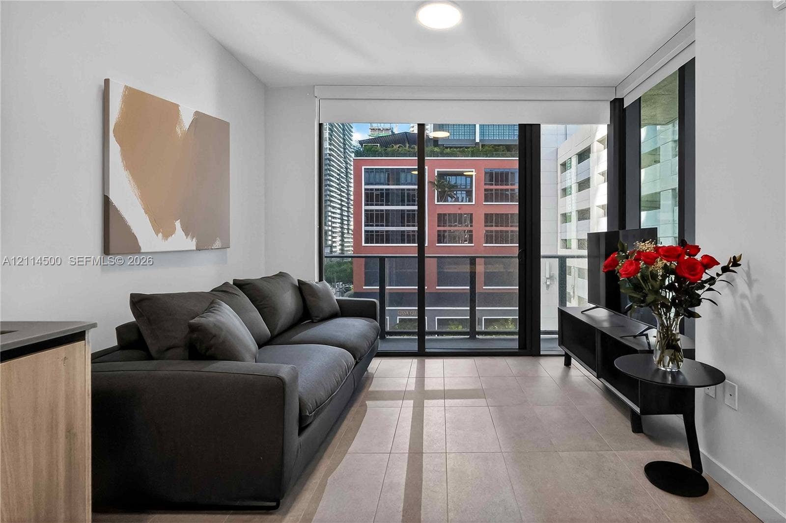 121 NE 5th Street, #712B, Miami, FL 33132 Floor-to-ceiling sliding glass doors, neutral tile flooring, and a private balcony with black metal railings