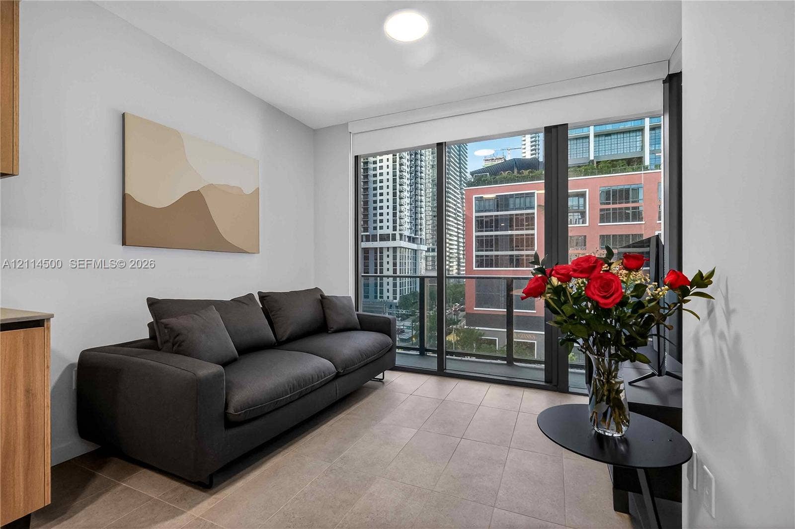 121 NE 5th Street, #712B, Miami, FL 33132 Floor-to-ceiling glass windows, neutral tile flooring, and integrated balcony access featuring metal railings
