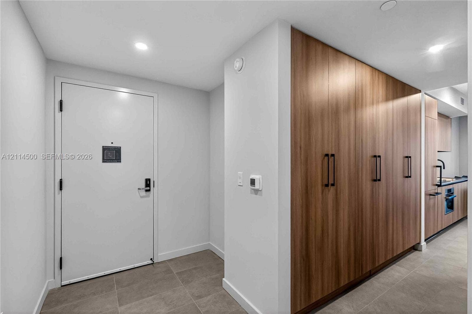 121 NE 5th Street, #712B, Miami, FL 33132 Entryway featuring large-format tile flooring, recessed ceiling lighting, and a floor-to-ceiling wood-finish cabinetry wall with matte black hardware
