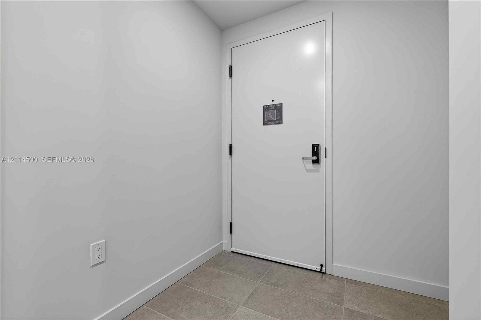 121 NE 5th Street, #712B, Miami, FL 33132 Interior entrance featuring a solid-core white door, matte black hardware, and neutral-toned floor tile