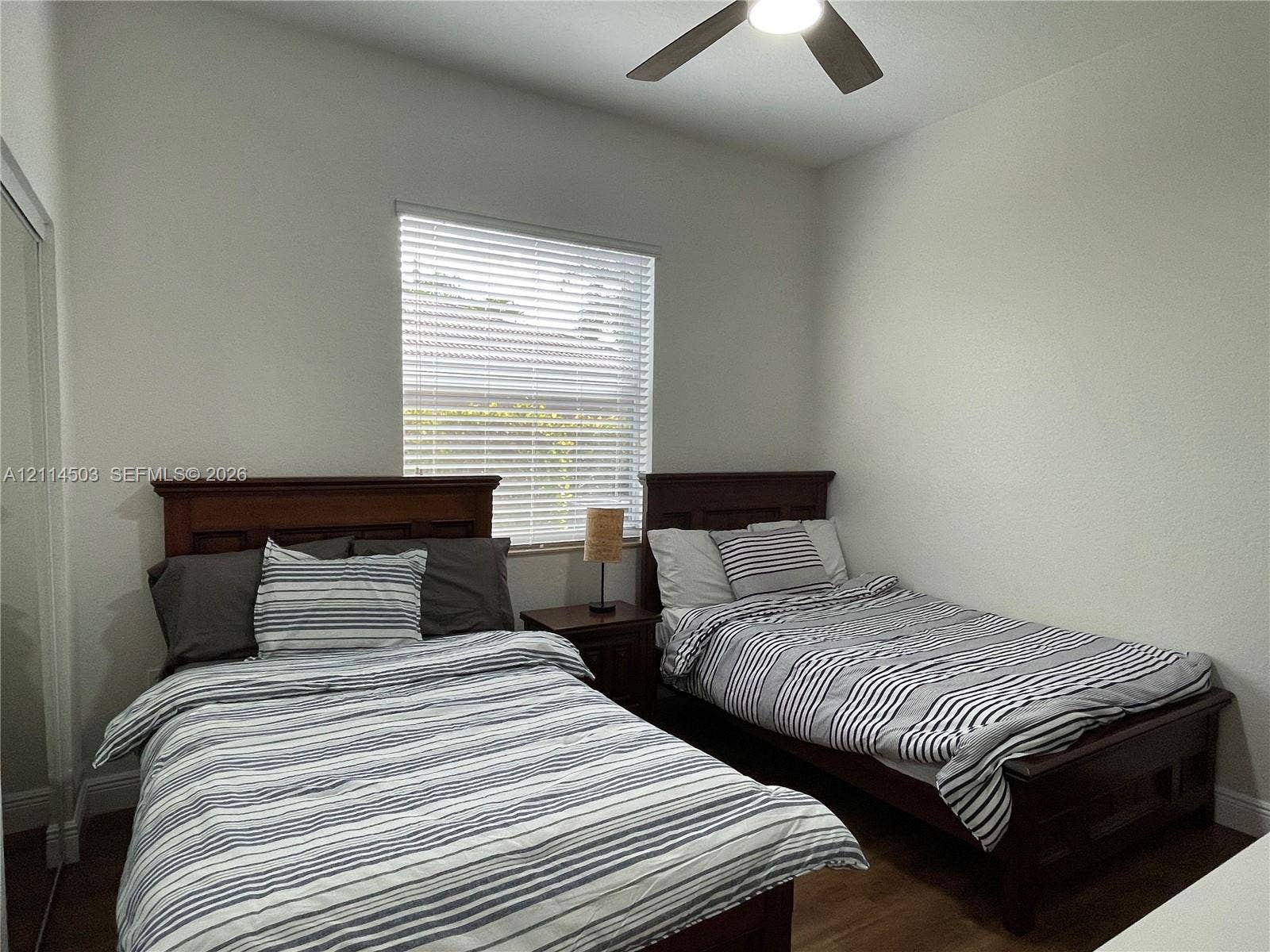 15001 SW 33rd Street, Davie, FL 33331 Neutral wall finishes, wood-finish flooring, ceiling fan with integrated lighting, and horizontal window blinds