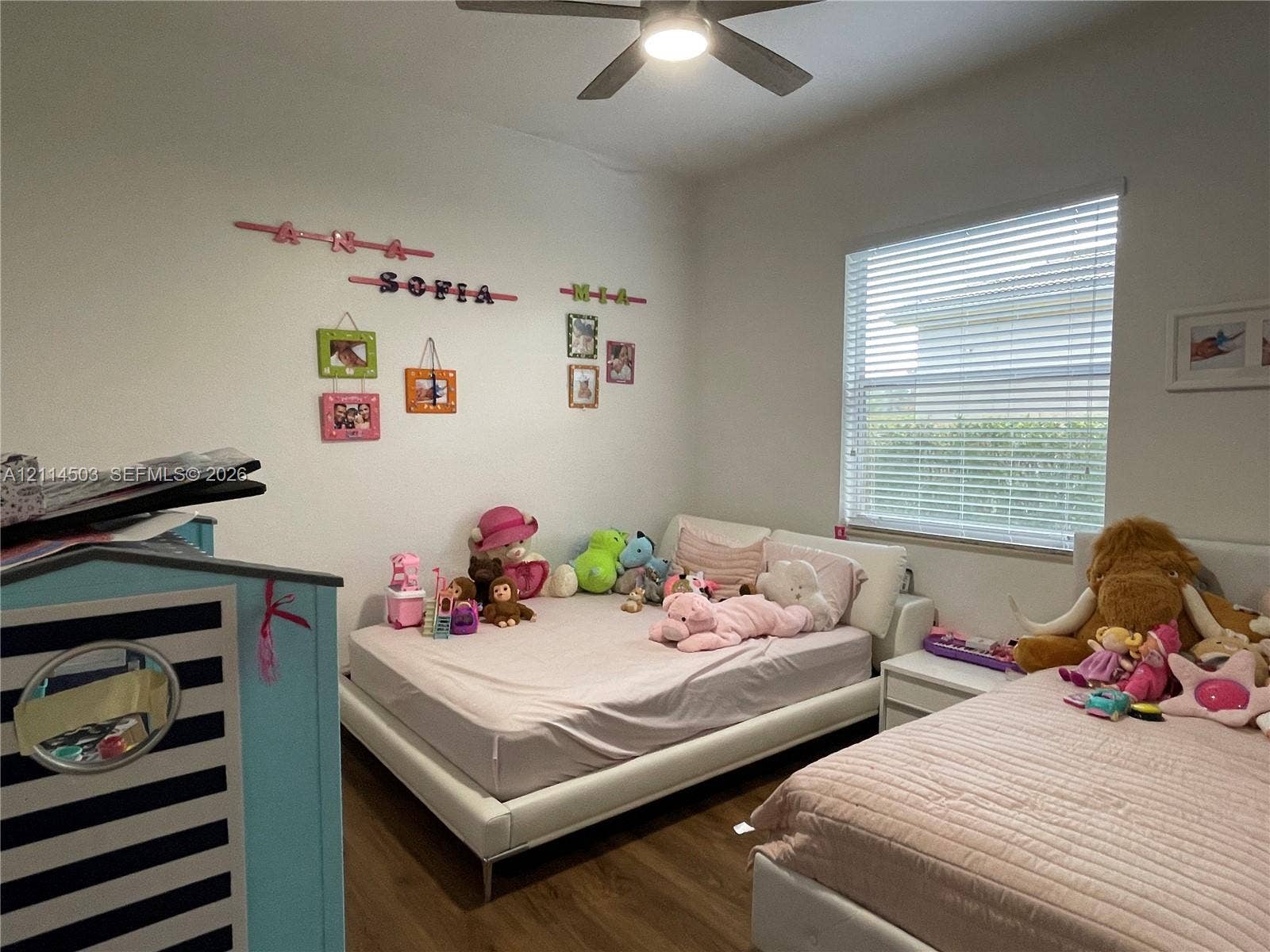 15001 SW 33rd Street, Davie, FL 33331 Bedroom featuring wood-finish flooring, a neutral color palette, a large window with horizontal blinds, and an integrated ceiling fan with light fixture