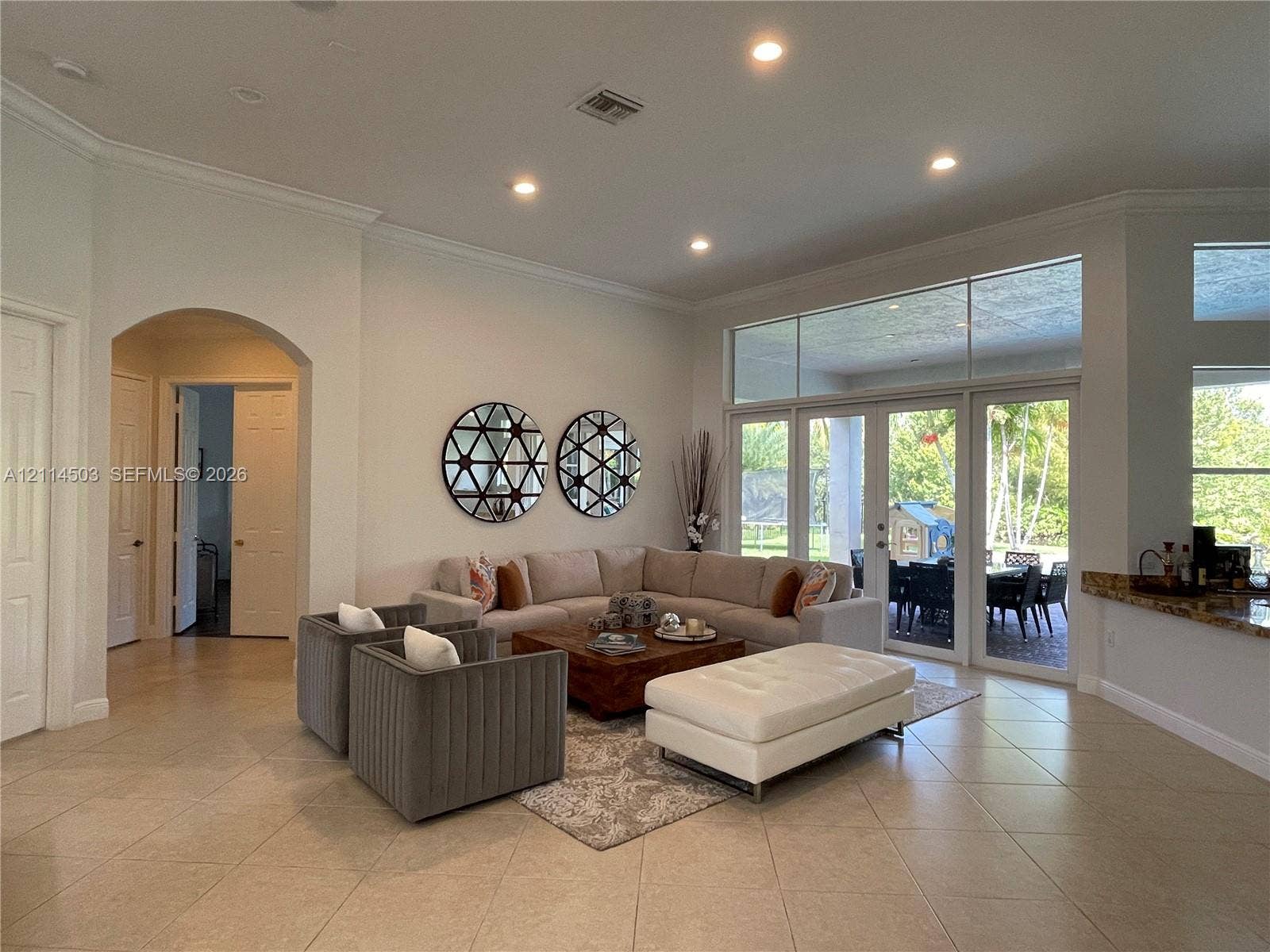 15001 SW 33rd Street, Davie, FL 33331 Open-concept living space featuring high ceilings with recessed lighting, large-format tile flooring, arched entryways, and floor-to-ceiling glass paneling with double doors