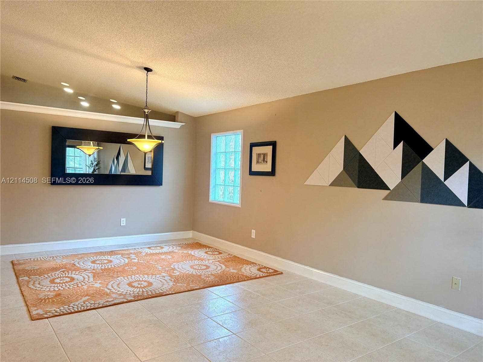 Ceramic tile flooring, crown molding, a hanging pendant light fixture, and a glass block window