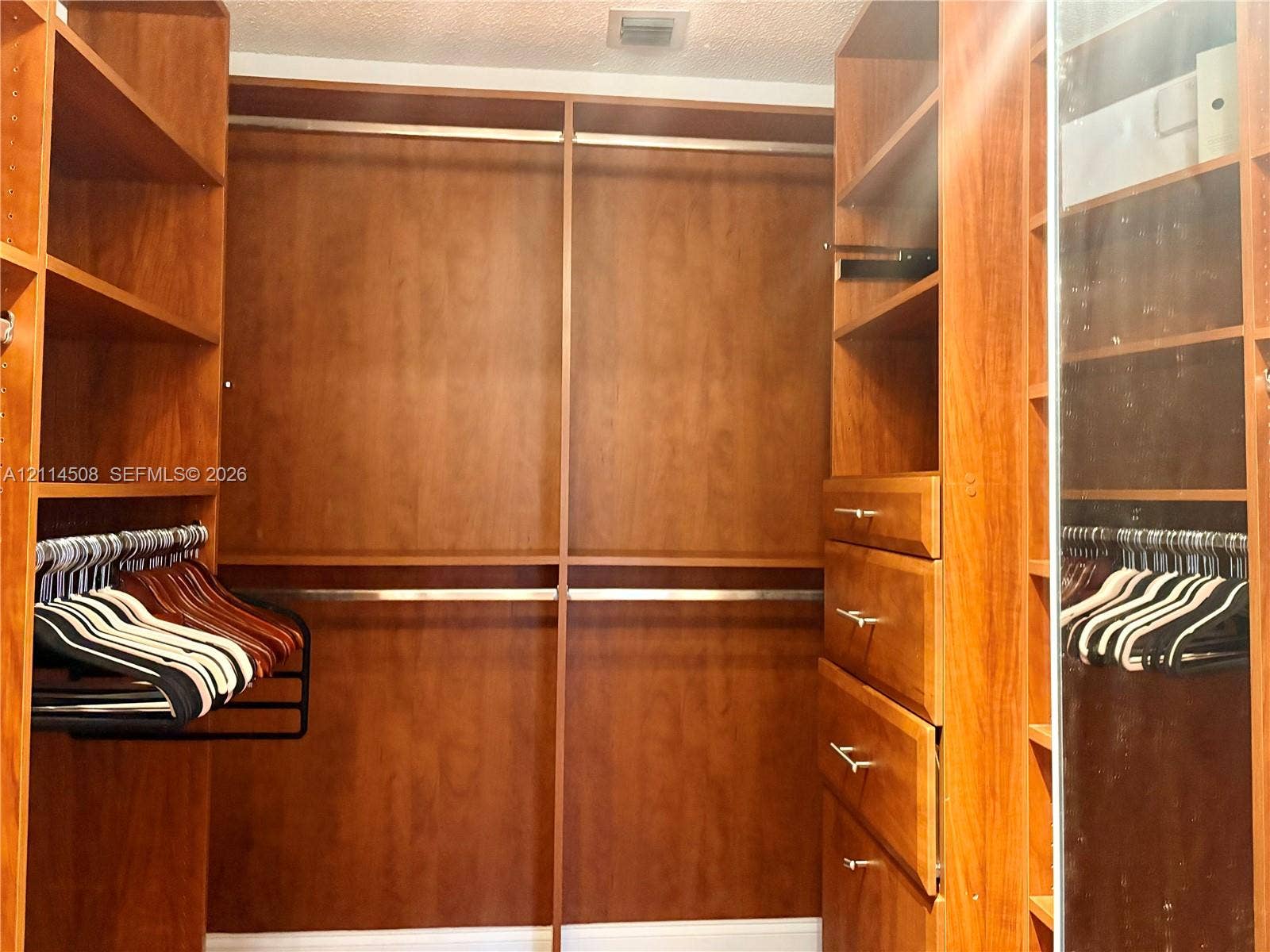 Customized wooden cabinetry featuring built-in shelving, four pull-out drawers with metal hardware, and integrated clothing rods