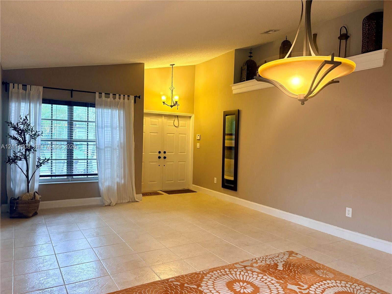 Vaulted ceilings, built-in recessed display shelving, ceramic tile flooring, double-entry front doors, and dual decorative hanging light fixtures