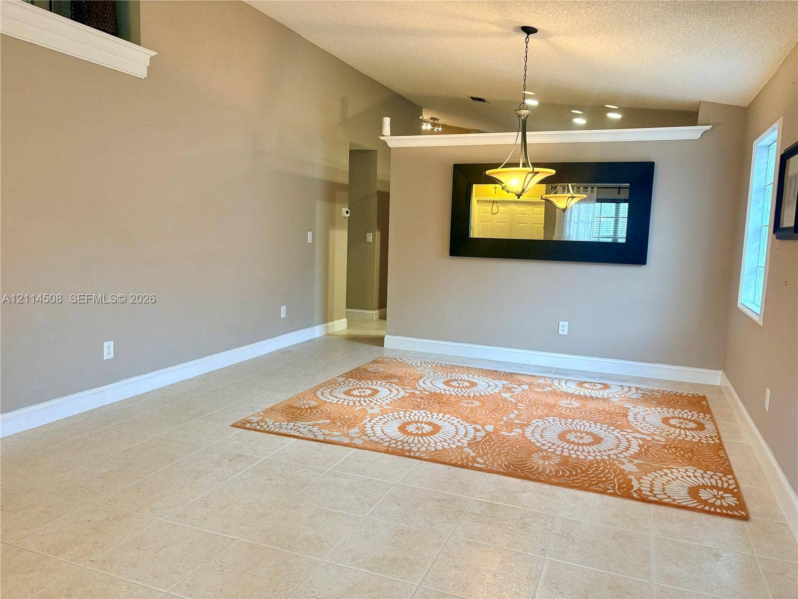 Vaulted ceilings, neutral wall tones, large-format tile flooring, crown molding accents, and a tiered architectural ledge
