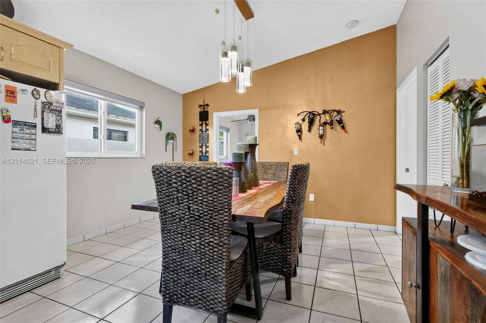 Vaulted ceiling, multi-pendant light fixture, tile flooring, and a single-hung window
