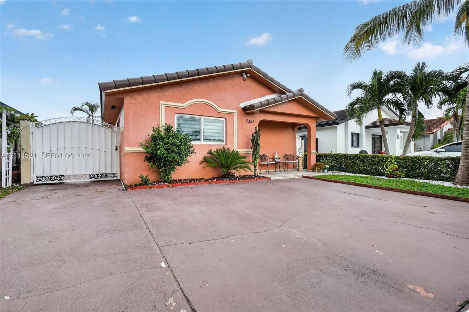 Stucco exterior featuring a covered entryway, tile roof, concrete driveway, and gated side access