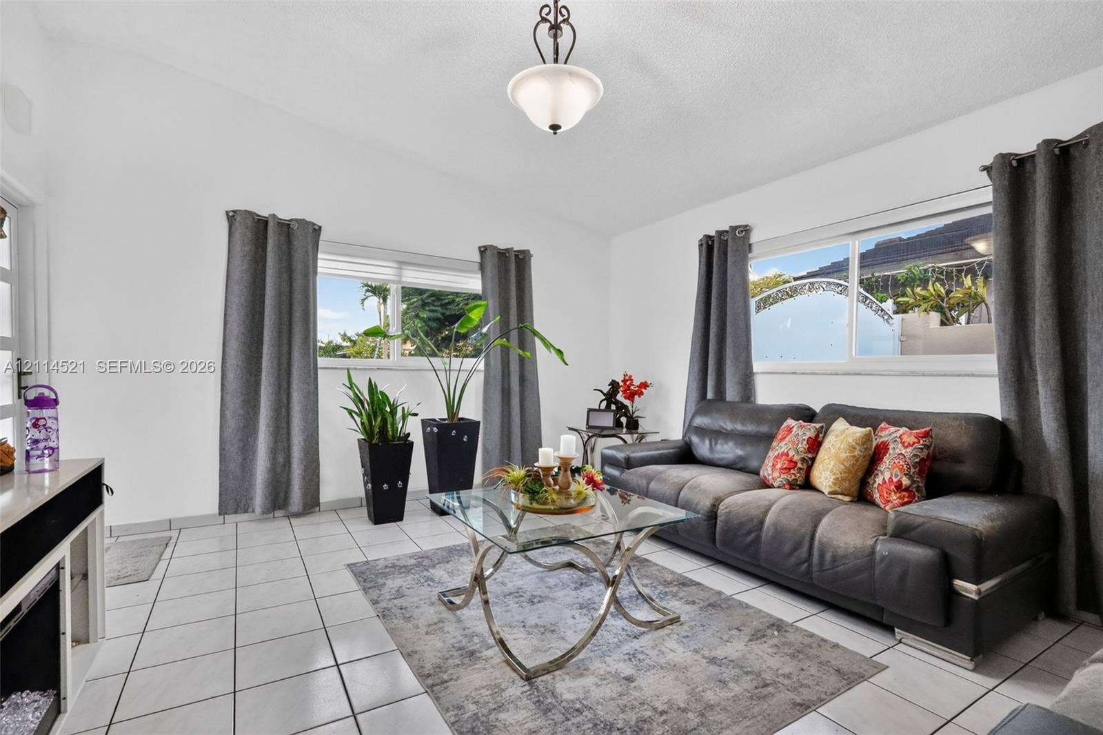 Living area featuring light-toned ceramic tile flooring, vaulted ceilings, dual-pane windows, and a central pendant light fixture