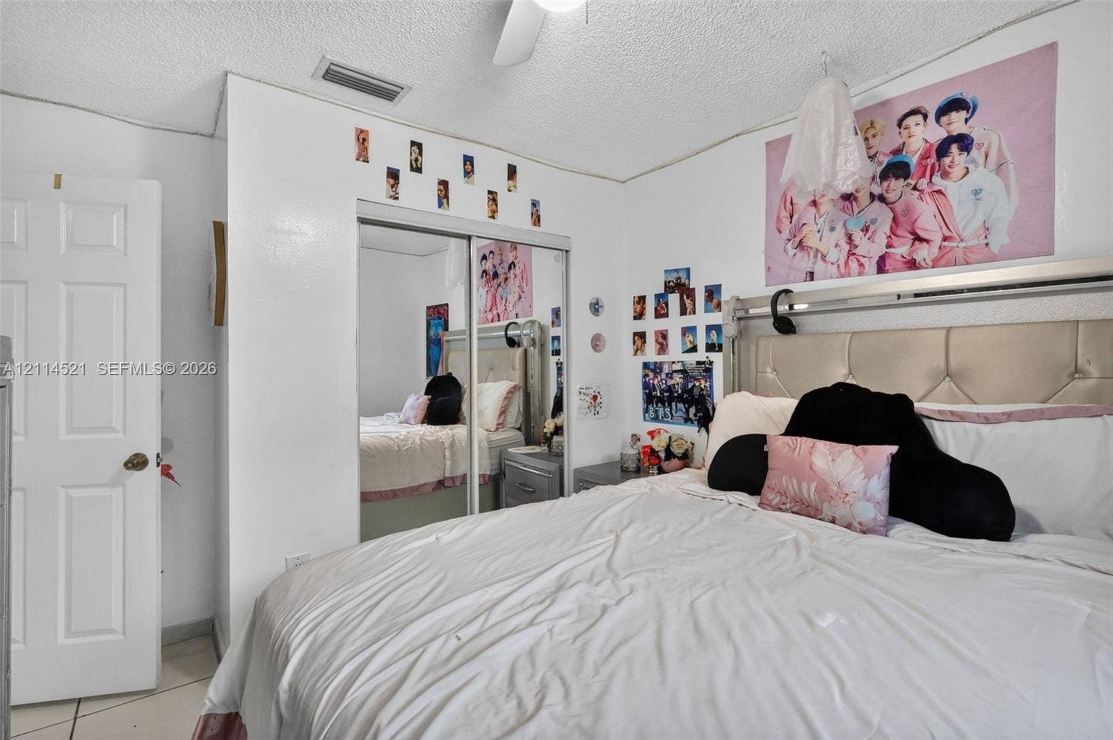 Room featuring white walls, dual mirrored sliding closet doors, a ceiling fan, and six-panel interior door