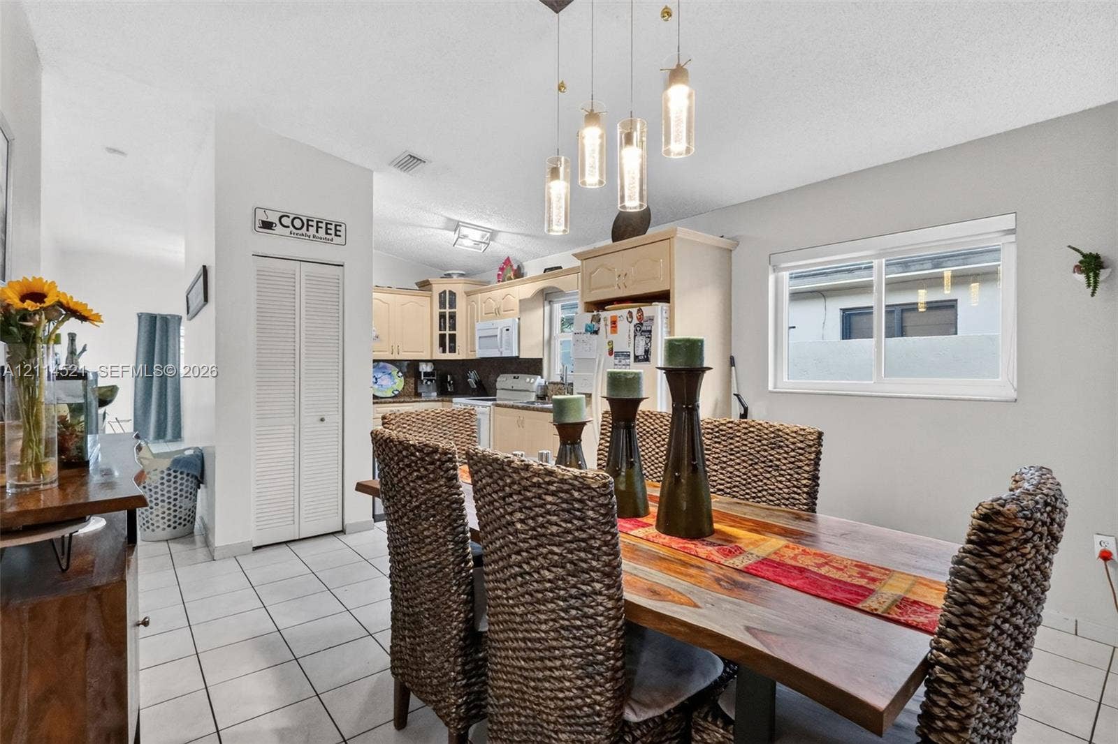 Dining area featuring ceramic tile flooring, a multi-light cylindrical glass pendant fixture, and white louvered closet doors