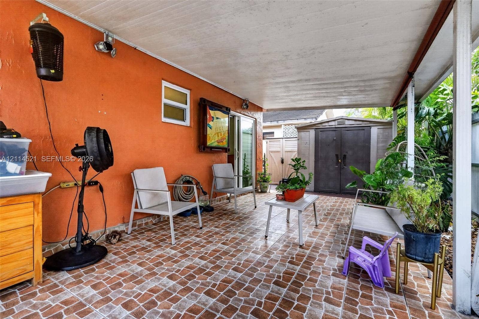 Covered patio featuring patterned tile flooring, a solid roof structure, and a sliding glass door