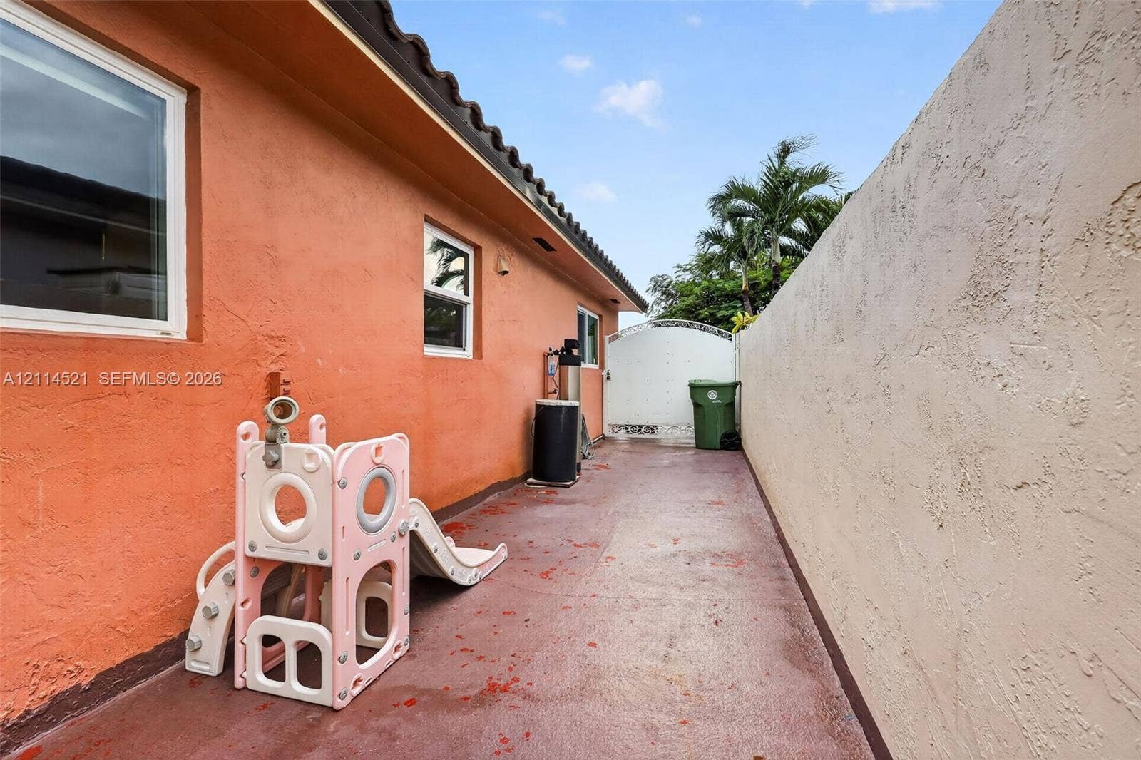 Side yard featuring stucco exterior walls, a concrete surface, and an enclosed perimeter wall with a gated entrance