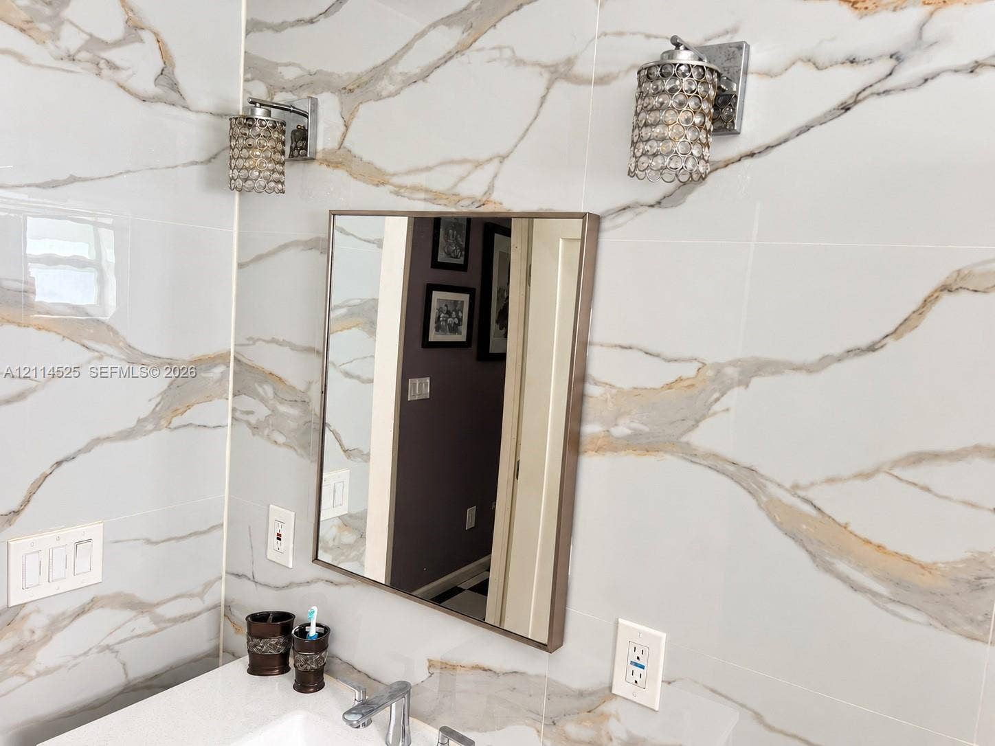 18905 SW 313th Terrace, Homestead, FL 33030 Large-format wall tiling with gold and gray veining, square mirror with metallic frame, and dual crystal-accented wall sconces