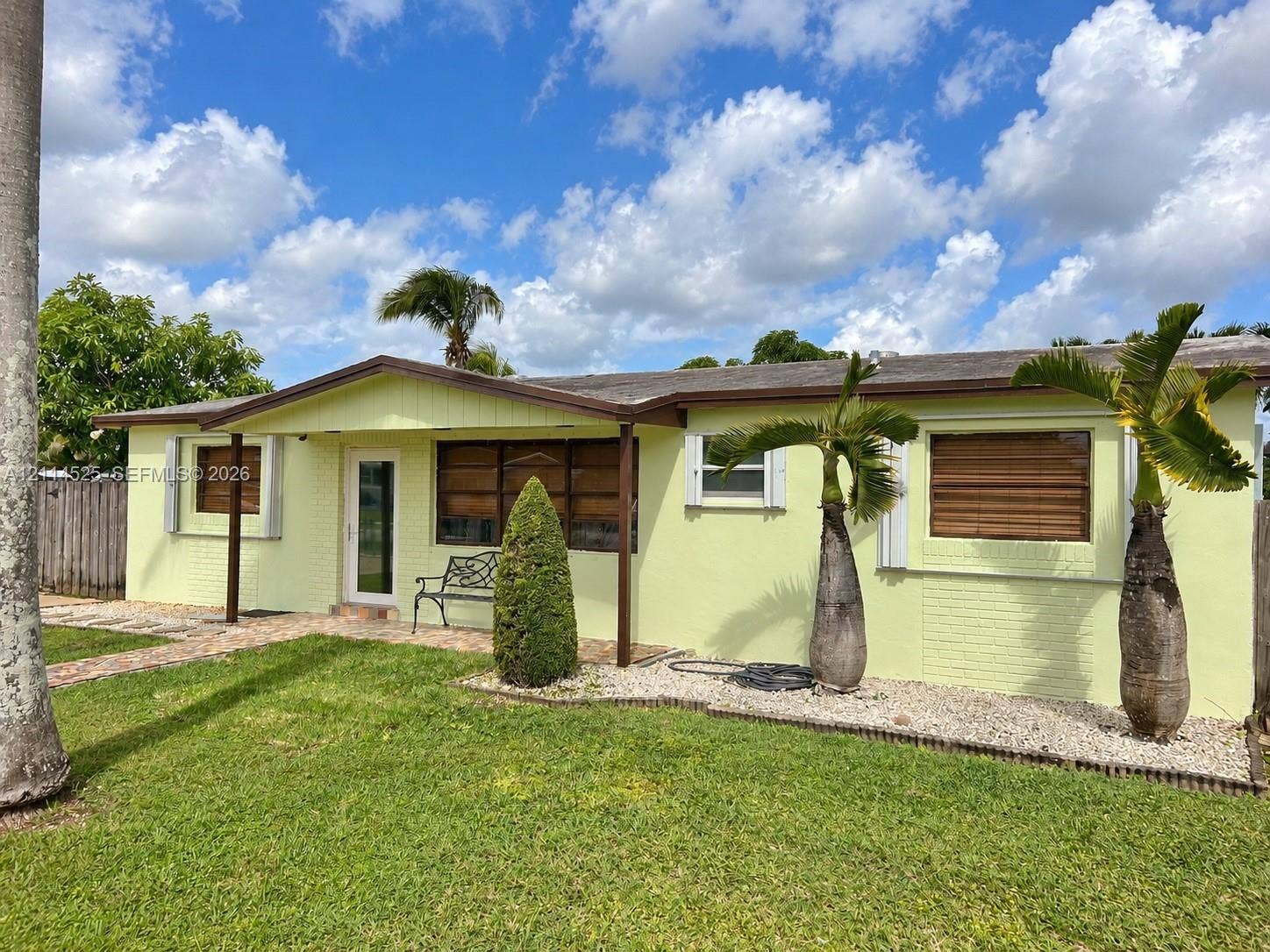 18905 SW 313th Terrace, Homestead, FL 33030 Single-story masonry exterior featuring a covered front porch, horizontal window shutters, and low-maintenance rock landscape beds