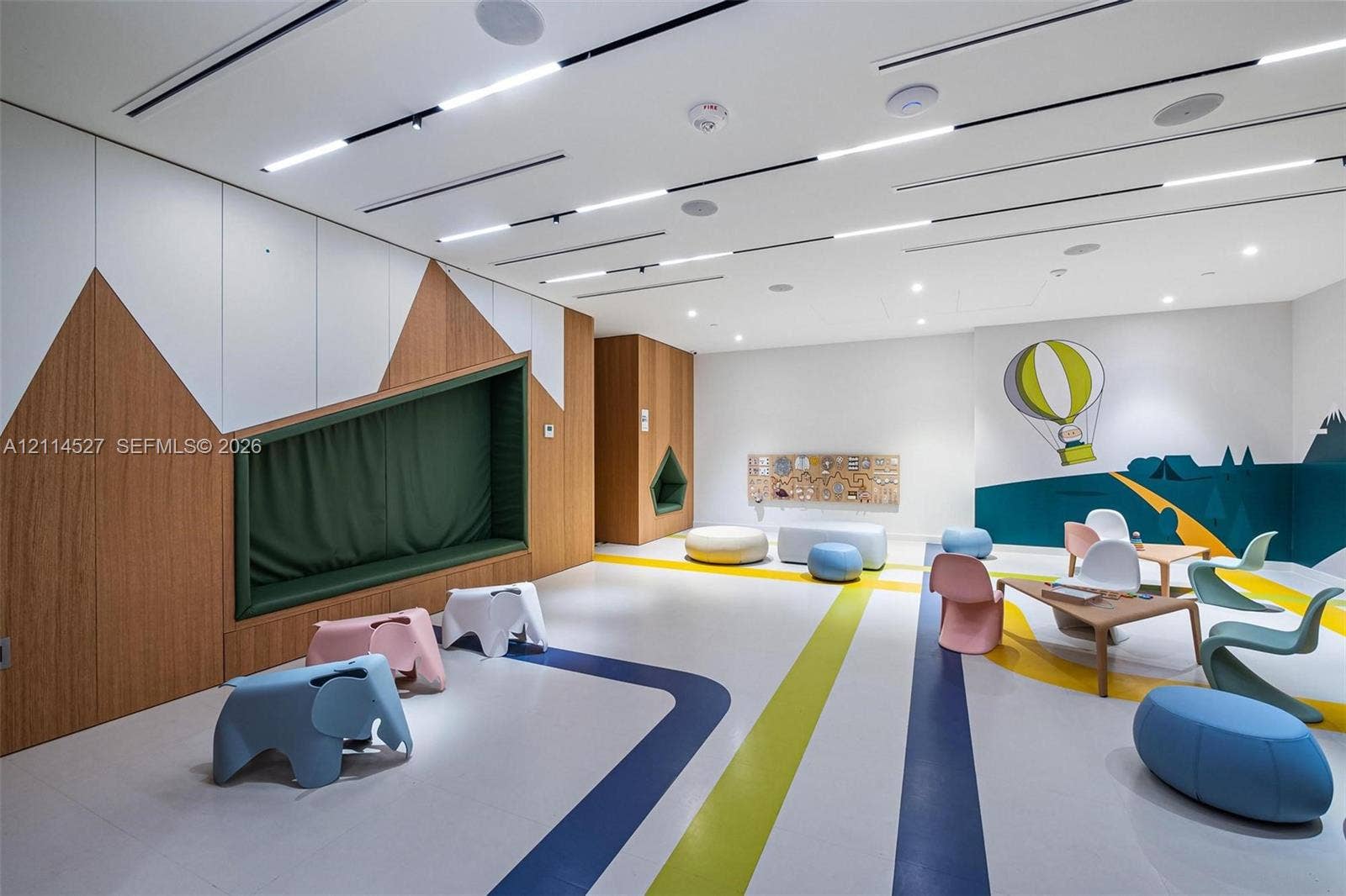 Custom wood-panel accent wall with integrated recessed seating, linear recessed ceiling lighting, smooth-finish flooring, and built-in wall niches