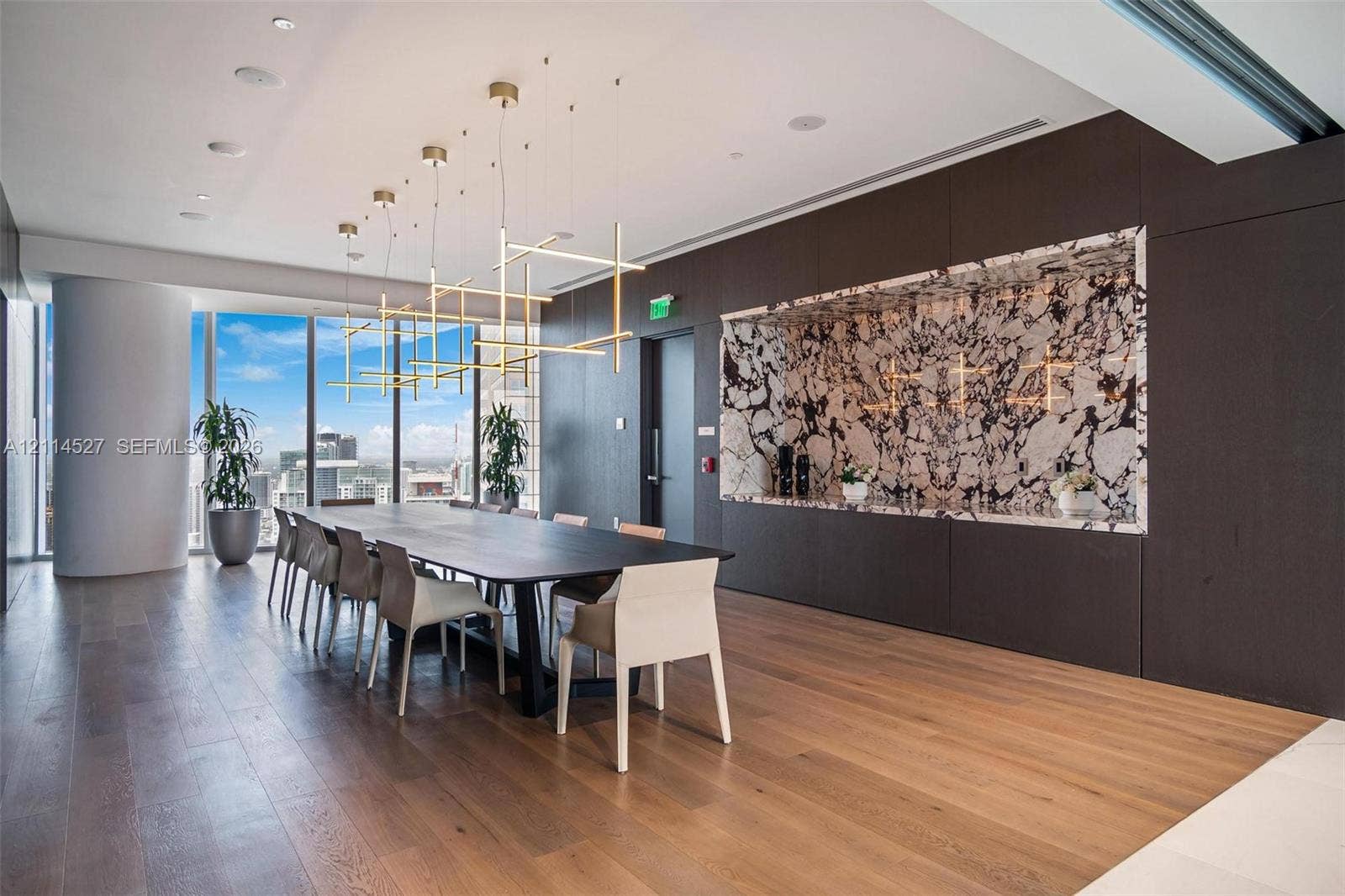 Floor-to-ceiling windows, wood-finish flooring, built-in recessed cabinetry featuring a contrasting stone backsplash, and multi-tier geometric pendant lighting