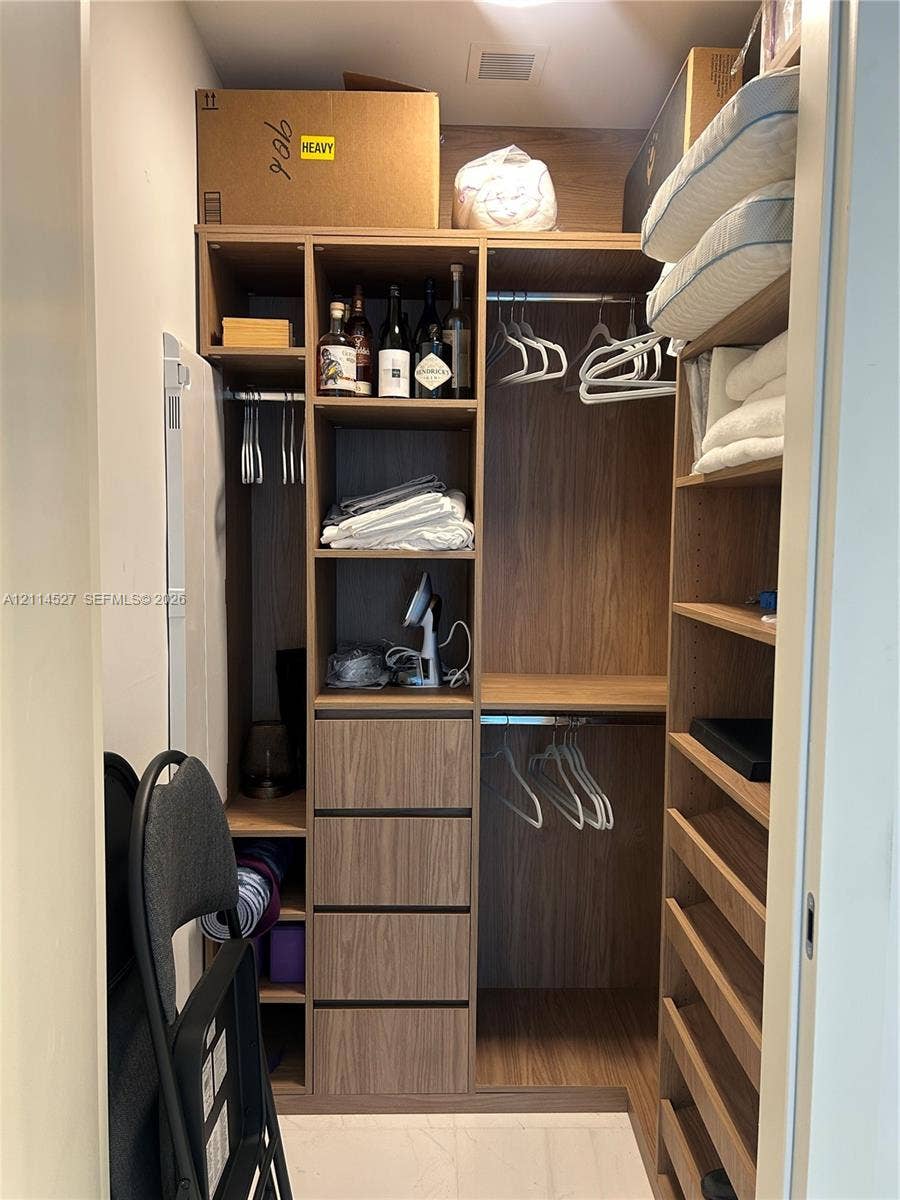 Custom closet organization system featuring wood-finish cabinetry, integrated shelving, four pull-out drawers, and dual hanging rods