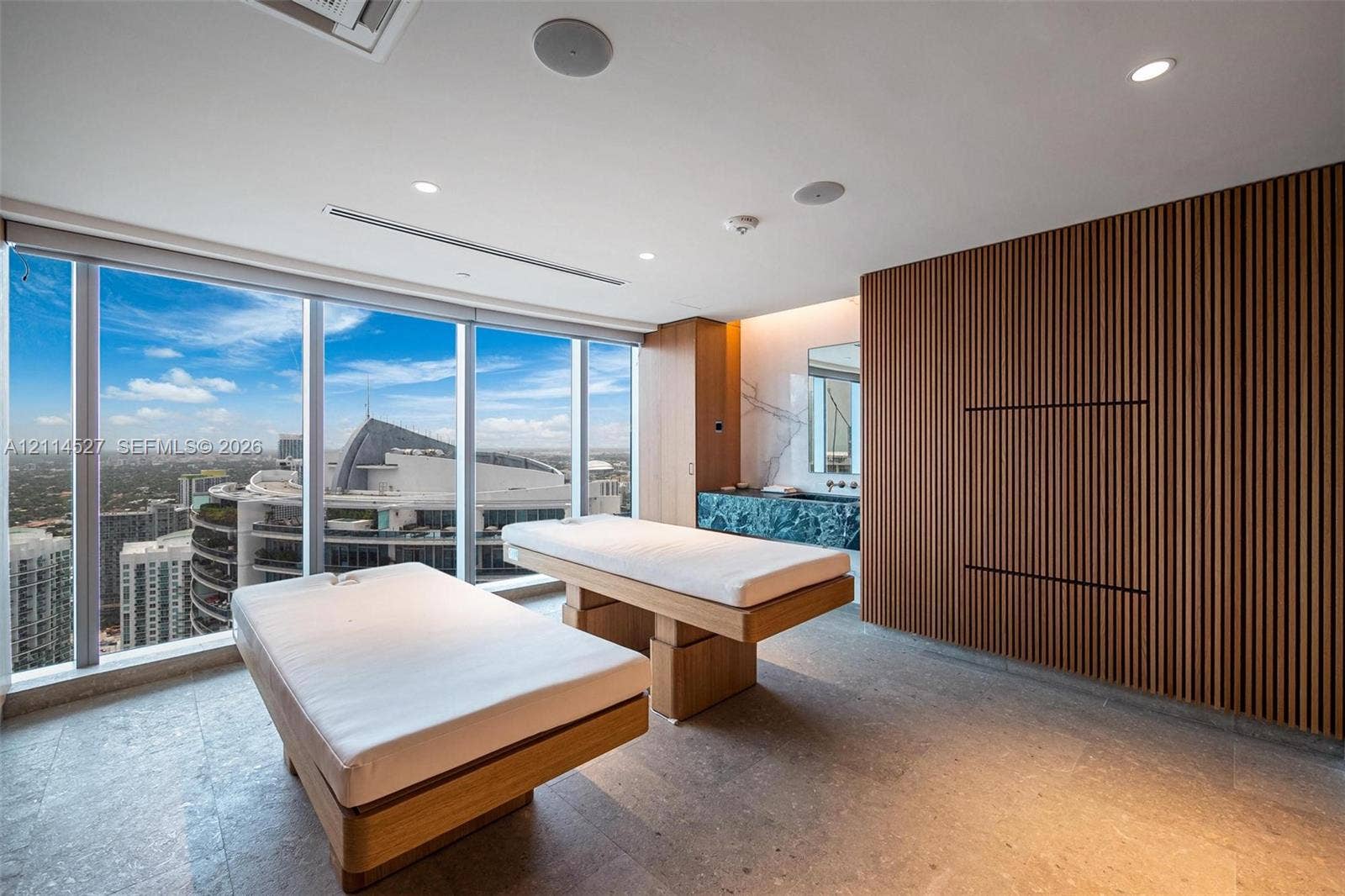Floor-to-ceiling windows, vertical wood-slat wall paneling, stone tile flooring, and integrated ceiling lighting