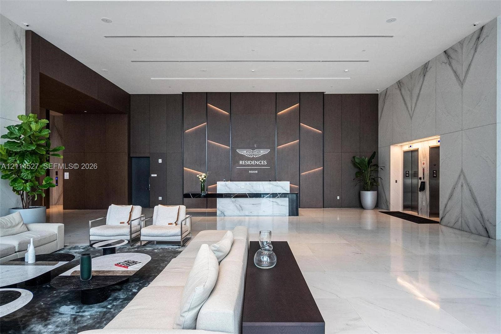 Grand lobby featuring polished stone flooring, custom wood-paneled feature wall with integrated accent lighting, built-in stone reception desk, and stone wall cladding