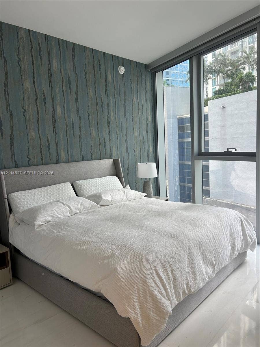 Floor-to-ceiling windows, textured accent wall, and polished tile flooring