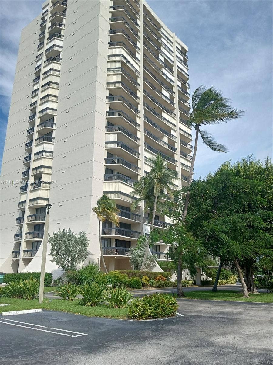 2400 Presidential Way, #1205, West Palm Beach, FL 33401 High-rise residential building featuring stacked private balconies, concrete exterior cladding, and ground-level landscaping