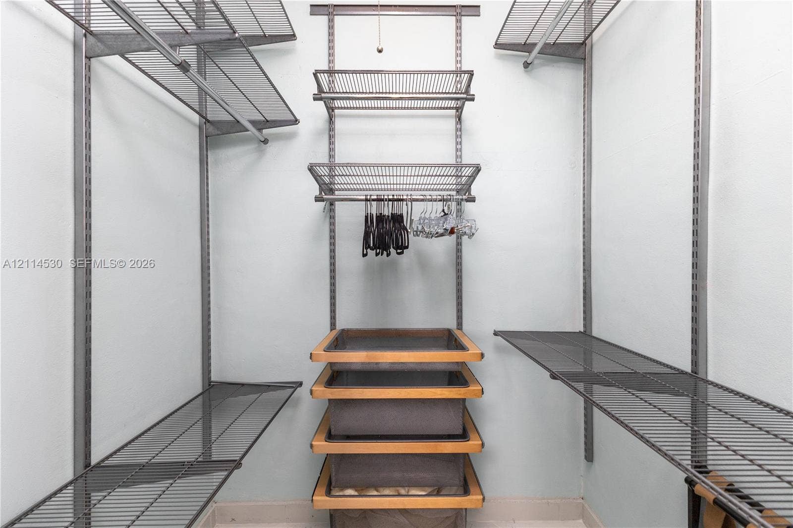 3 Island Avenue, #14L, Miami Beach, FL 33139 Walk-in closet featuring adjustable metal wire shelving, wall-mounted vertical standards, and a central built-in unit with four slide-out fabric storage baskets framed in wood trim