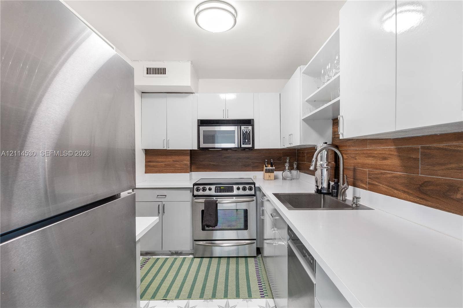 3 Island Avenue, #14L, Miami Beach, FL 33139 Kitchen featuring stainless steel appliances, white gloss cabinetry, solid surface countertops, and wood-finish tile backsplash