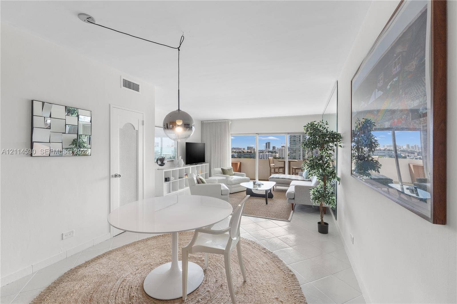 3 Island Avenue, #14L, Miami Beach, FL 33139 Living area featuring large-format ceramic tile flooring, floor-to-ceiling glass sliding doors, a polished metallic spherical pendant light, and a full-wall mirror