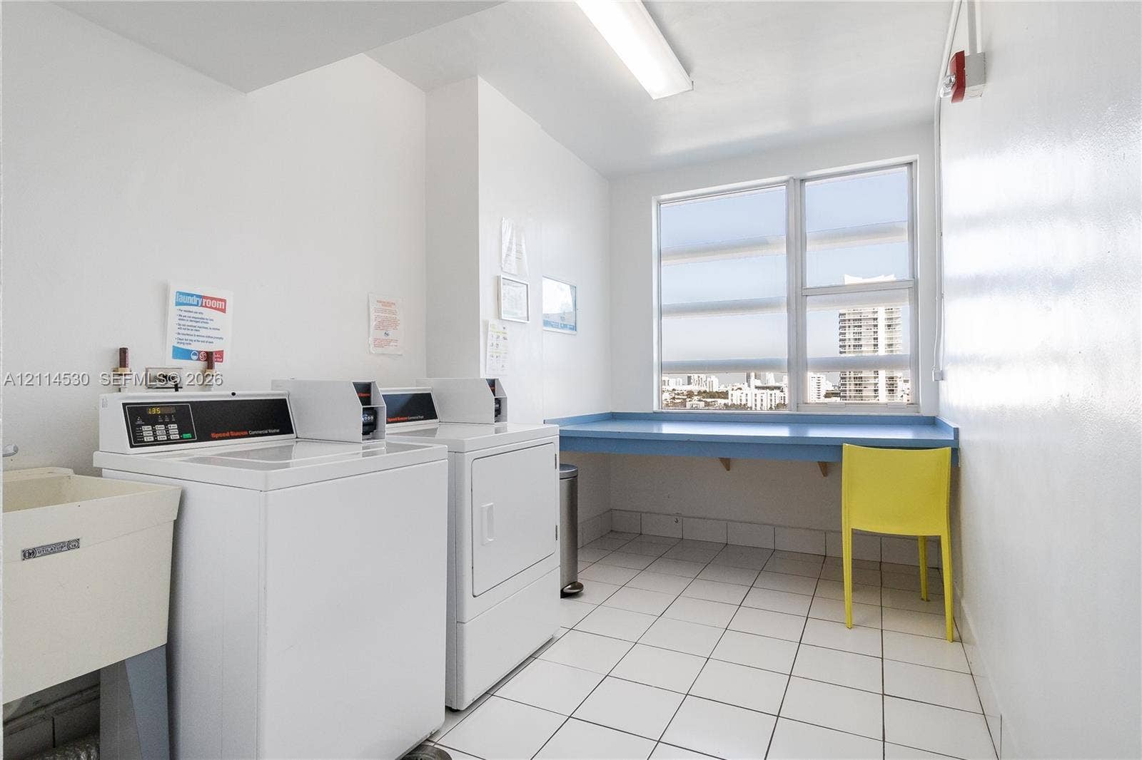 3 Island Avenue, #14L, Miami Beach, FL 33139 Laundry room featuring white tile flooring, large multi-pane windows, and a built-in folding counter