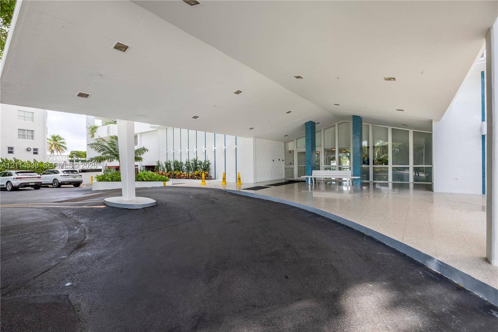 3 Island Avenue, #14L, Miami Beach, FL 33139 Covered porte-cochre entry featuring recessed lighting, a paved drop-off area, blue decorative columns, and full-height glass storefront glazing