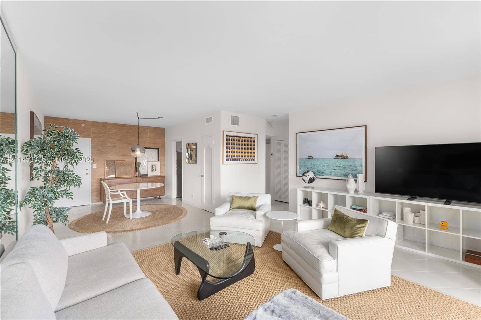 3 Island Avenue, #14L, Miami Beach, FL 33139 Open-concept living space featuring high ceilings, light-toned flooring, wall-to-wall mirror paneling, and a distinct wood-paneled accent wall