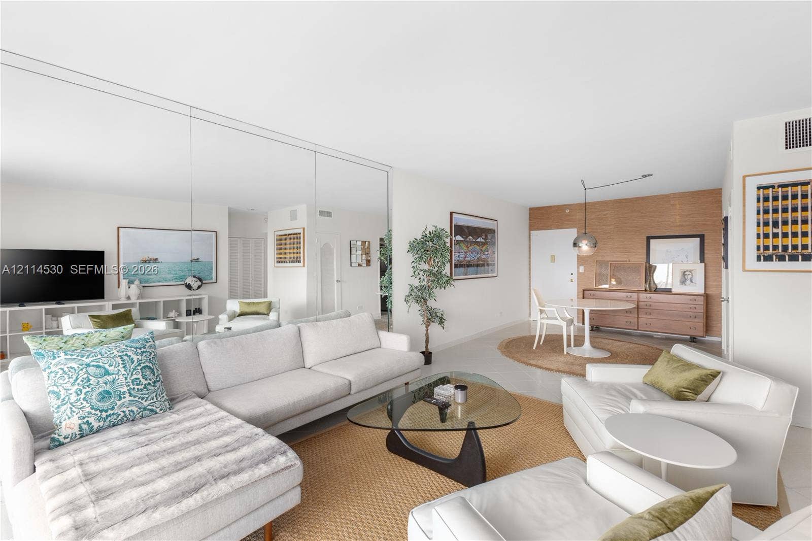 3 Island Avenue, #14L, Miami Beach, FL 33139 Living area featuring floor-to-ceiling mirrored walls, smooth-finish ceilings, wood-paneled accent wall, and neutral tile flooring