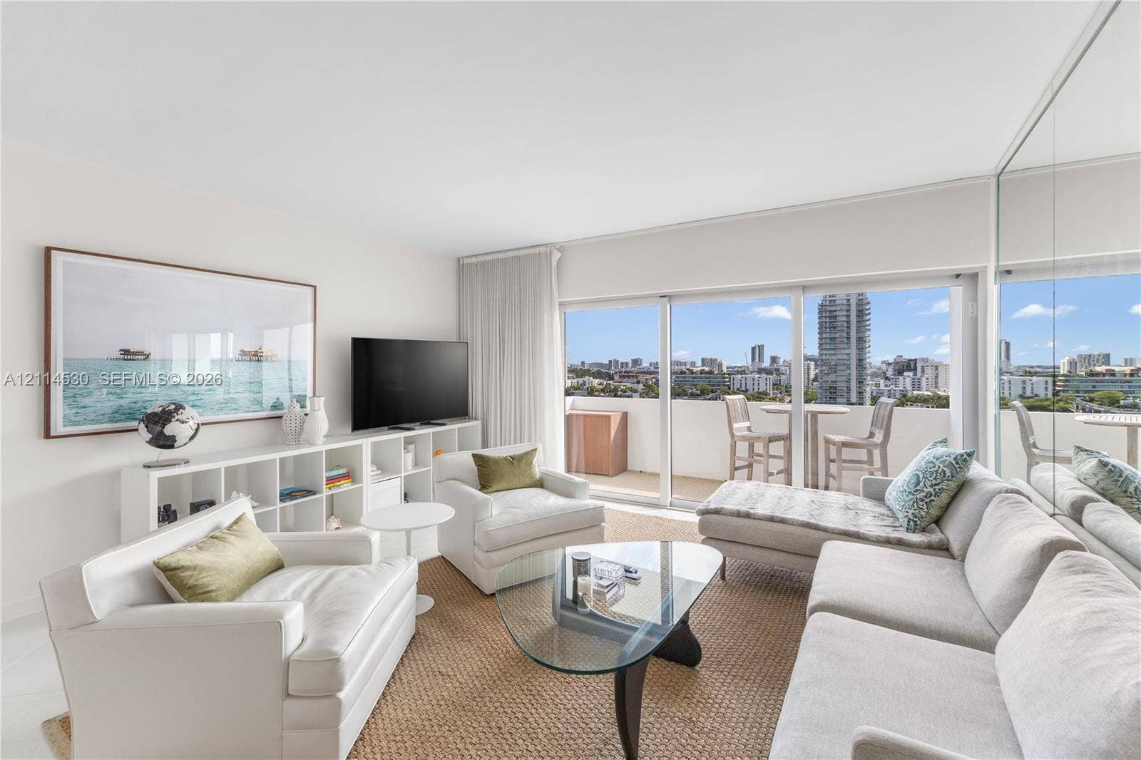 3 Island Avenue, #14L, Miami Beach, FL 33139 Living area featuring full-height glass sliding doors, private balcony, floor-to-ceiling mirrored wall, and built-in shelving unit