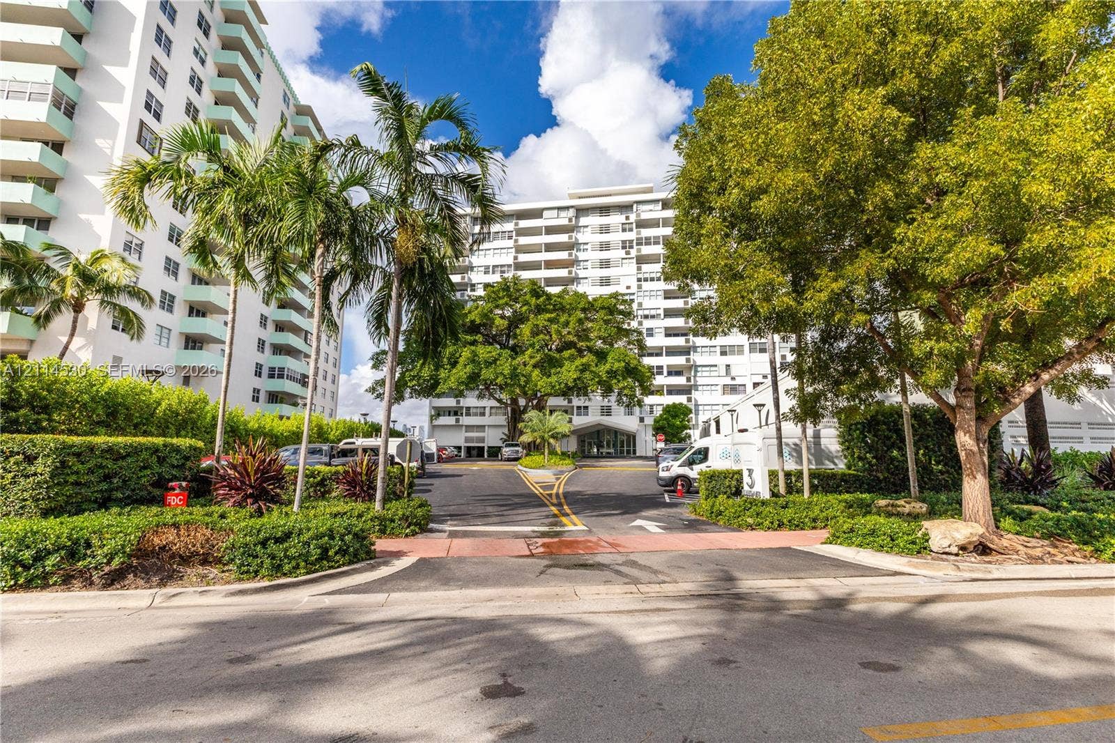 3 Island Avenue, #14L, Miami Beach, FL 33139 High-rise residential exterior featuring white balconies, asphalt driveways, mature landscaping, and palm trees