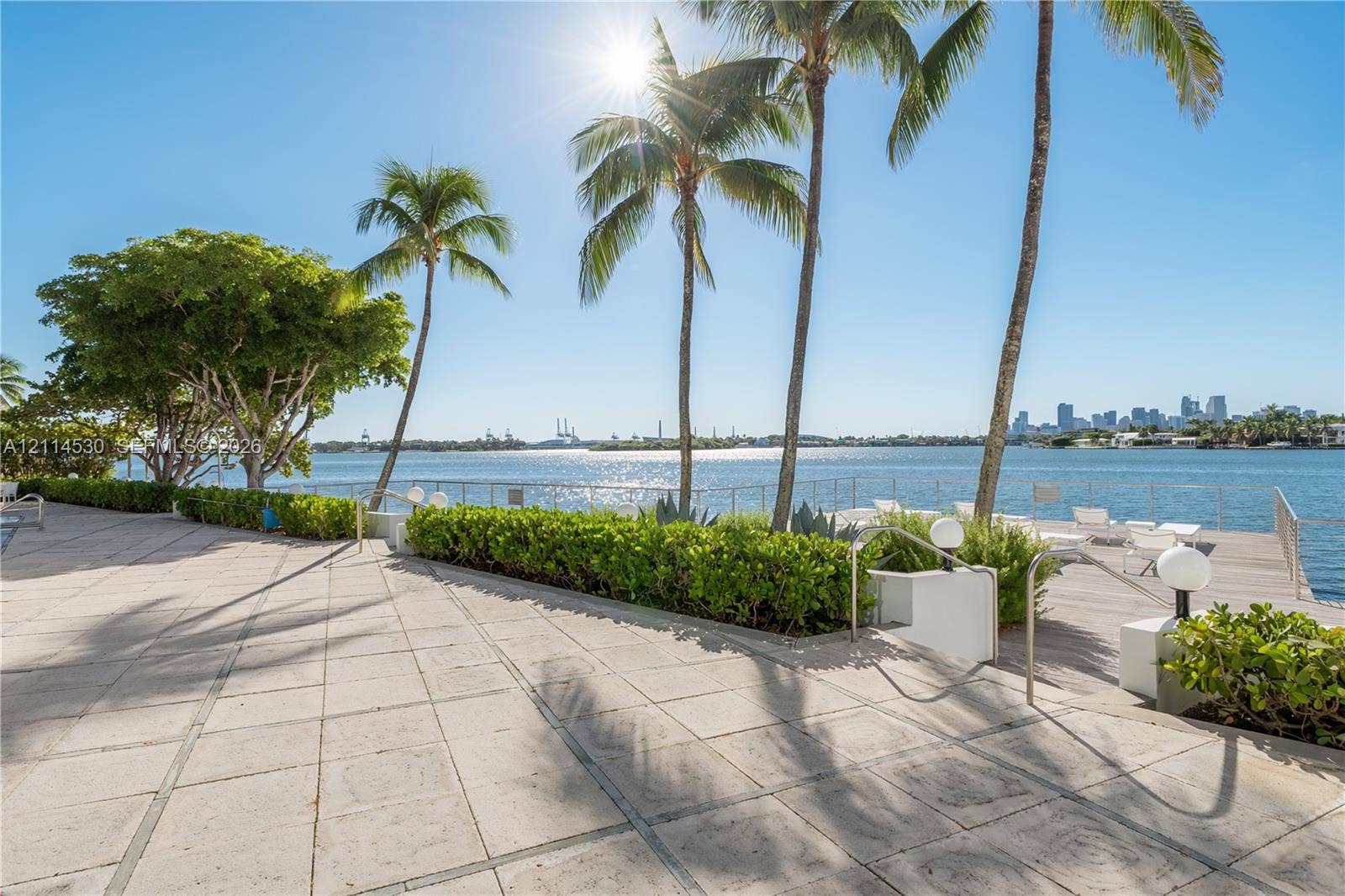 3 Island Avenue, #14L, Miami Beach, FL 33139 Waterfront terrace featuring stone paver flooring, perimeter metal railings, mature palm trees, and manicured shrubbery