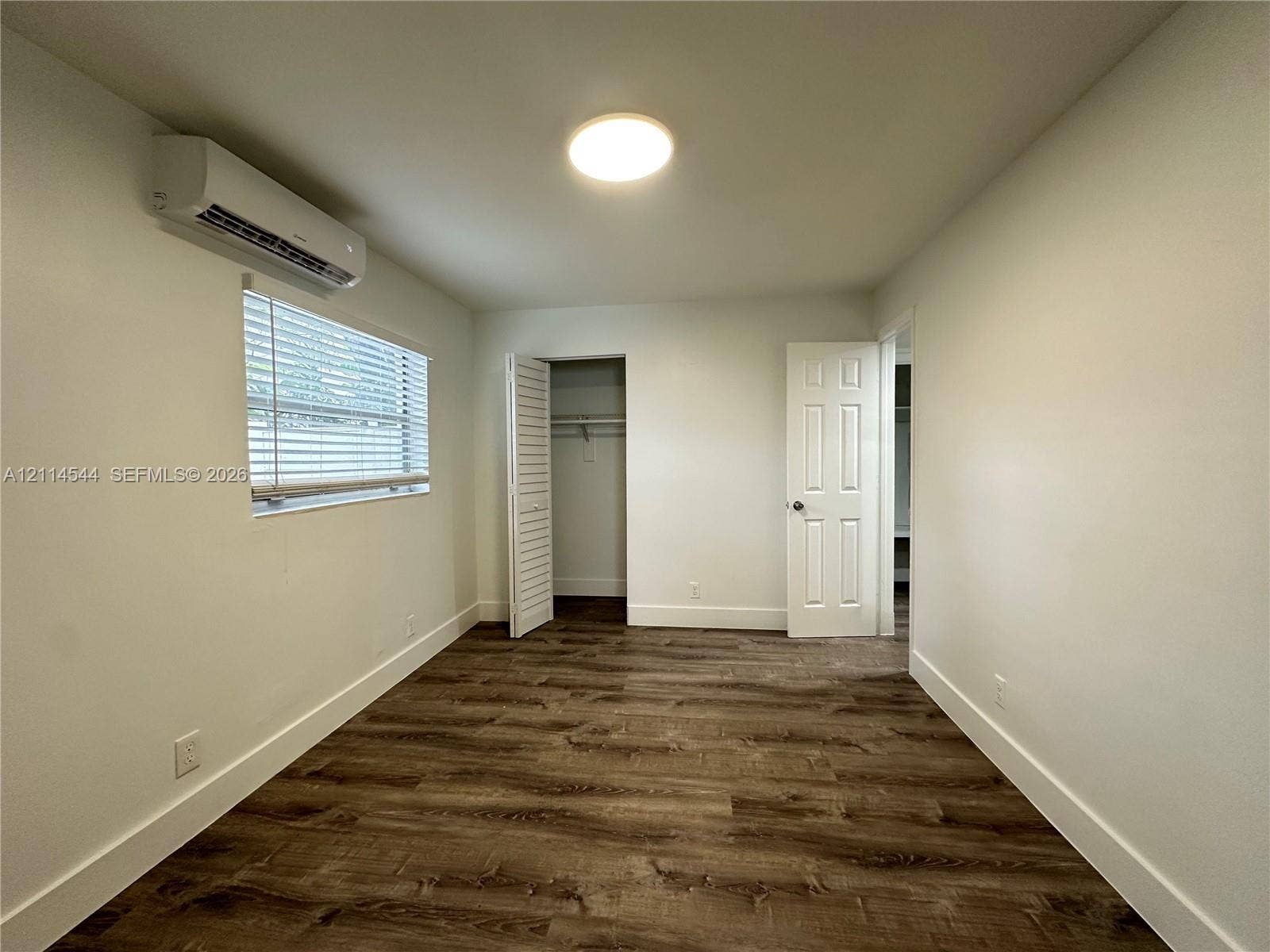 1413 N Dixie Highway, #3, Fort Lauderdale, Fort Lauderdale, FL 33304 Interior space featuring wood-finish flooring, a wall-mounted ductless mini-split climate control system, a closet with louvered doors, a flush-mount ceiling light, and a six-panel door