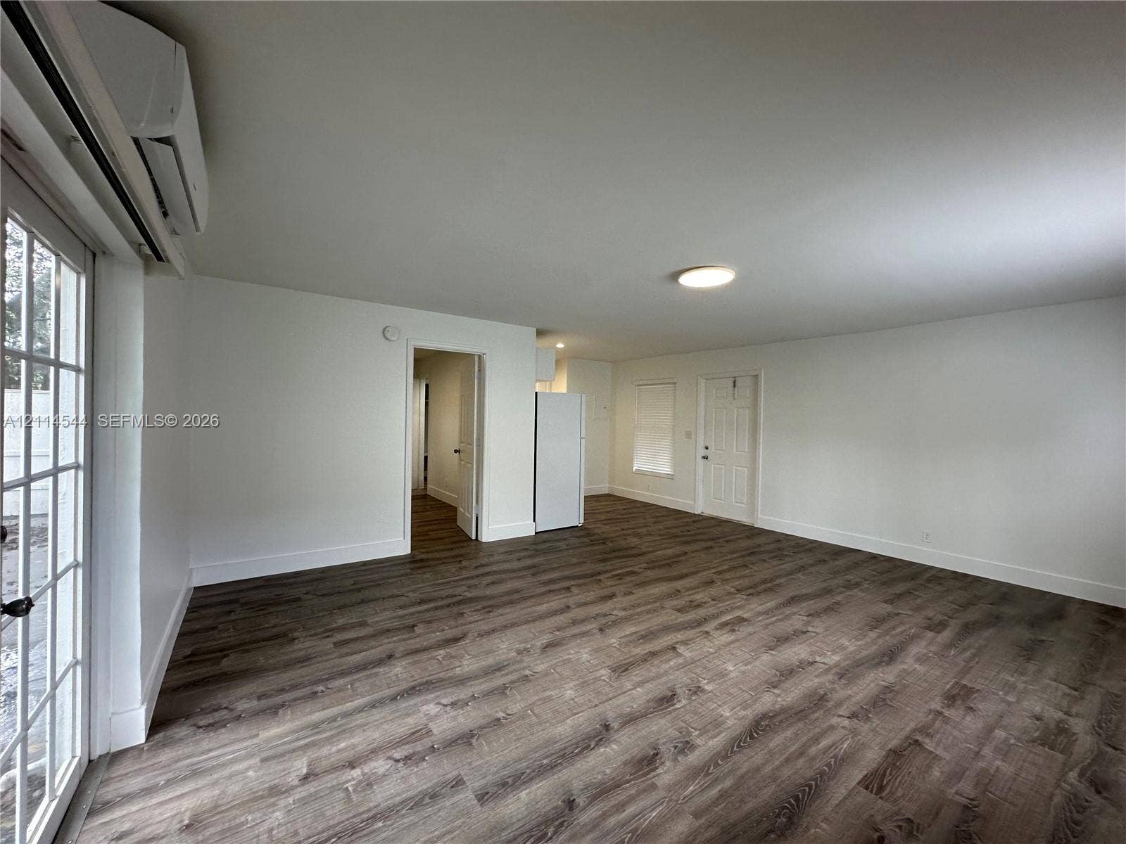 1413 N Dixie Highway, #3, Fort Lauderdale, Fort Lauderdale, FL 33304 Open-concept interior featuring wood-finish flooring, a wall-mounted ductless heating and cooling unit, flush-mount ceiling lighting, and a multi-pane glass door