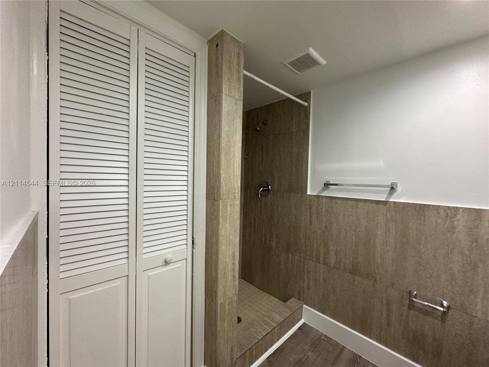 1413 N Dixie Highway, #3, Fort Lauderdale, Fort Lauderdale, FL 33304 Walk-in shower featuring large-format stone-textured tile, white louvered-door closet, metallic hardware, and wood-finish flooring