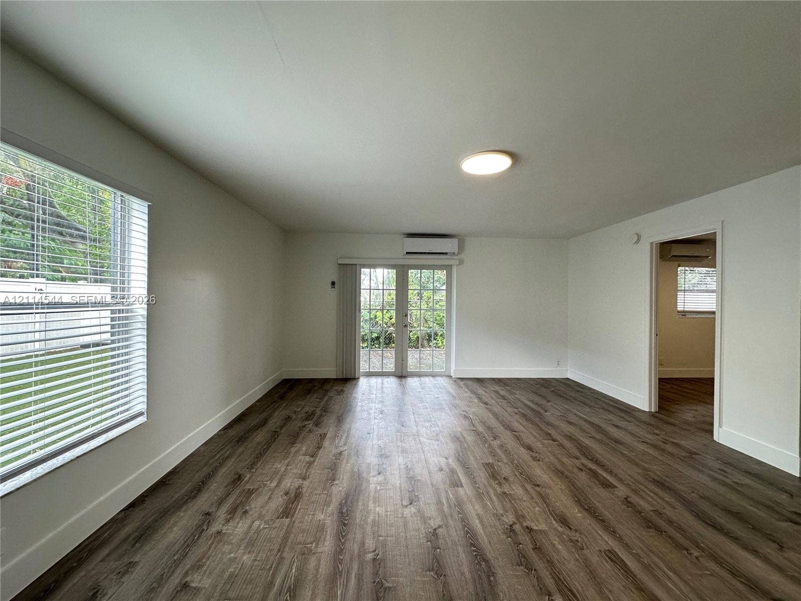 1413 N Dixie Highway, #3, Fort Lauderdale, Fort Lauderdale, FL 33304 Wood-finish flooring, glass-paneled double doors, wall-mounted ductless air conditioning unit, and horizontal blind window treatments