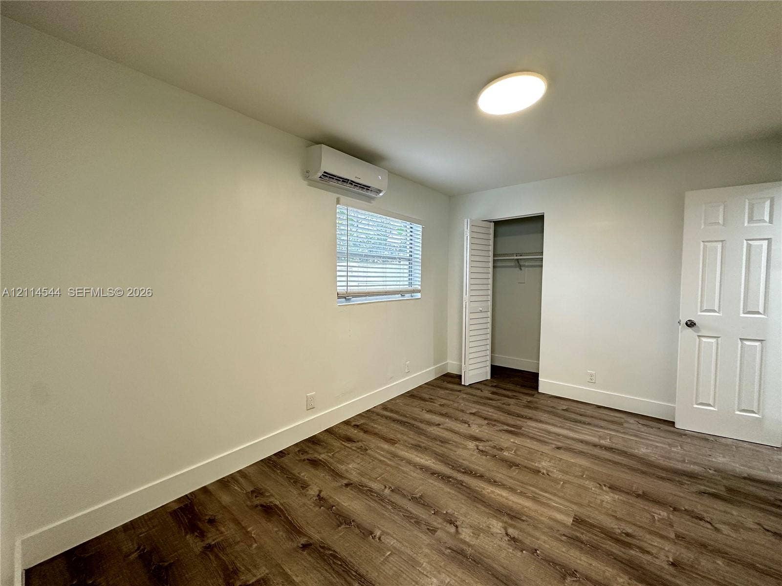 1413 N Dixie Highway, #3, Fort Lauderdale, Fort Lauderdale, FL 33304 Room featuring wood-finish flooring, a wall-mounted ductless air conditioning unit, flush-mount ceiling lighting, a louvered-door closet, and a six-panel interior door