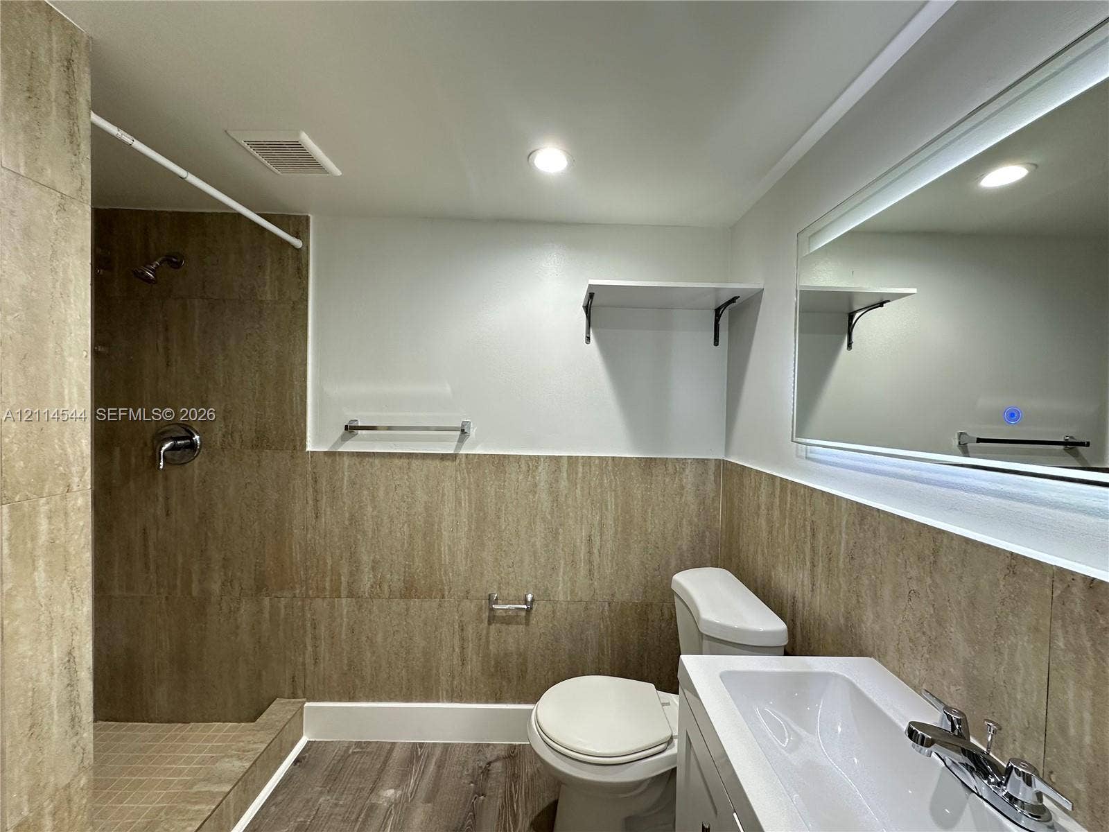 1413 N Dixie Highway, #3, Fort Lauderdale, Fort Lauderdale, FL 33304 Bathroom featuring walk-in shower with floor-to-ceiling textured tile, wood-finish flooring, white vanity with integrated sink, and an illuminated wall-mounted mirror