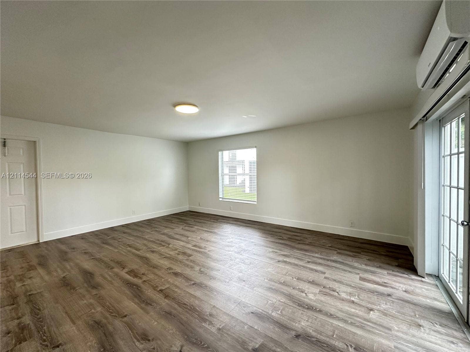 1413 N Dixie Highway, #3, Fort Lauderdale, Fort Lauderdale, FL 33304 Neutral-toned interior featuring wood-finish flooring, a wall-mounted ductless heating and cooling unit, flush-mount ceiling lighting, and a glass-paned exterior door