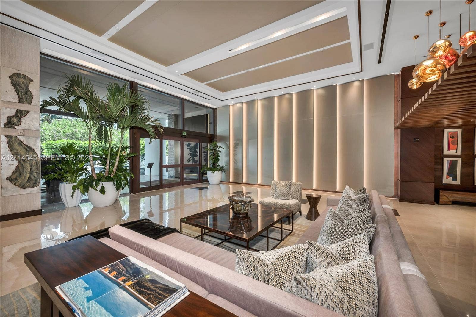 5875 Collins Avenue, #1503, Miami Beach, FL 33140 High-ceilinged foyer featuring polished stone flooring, recessed coffered ceiling, wall-integrated vertical lighting, floor-to-ceiling glass entry doors, and wood-slat ceiling accents