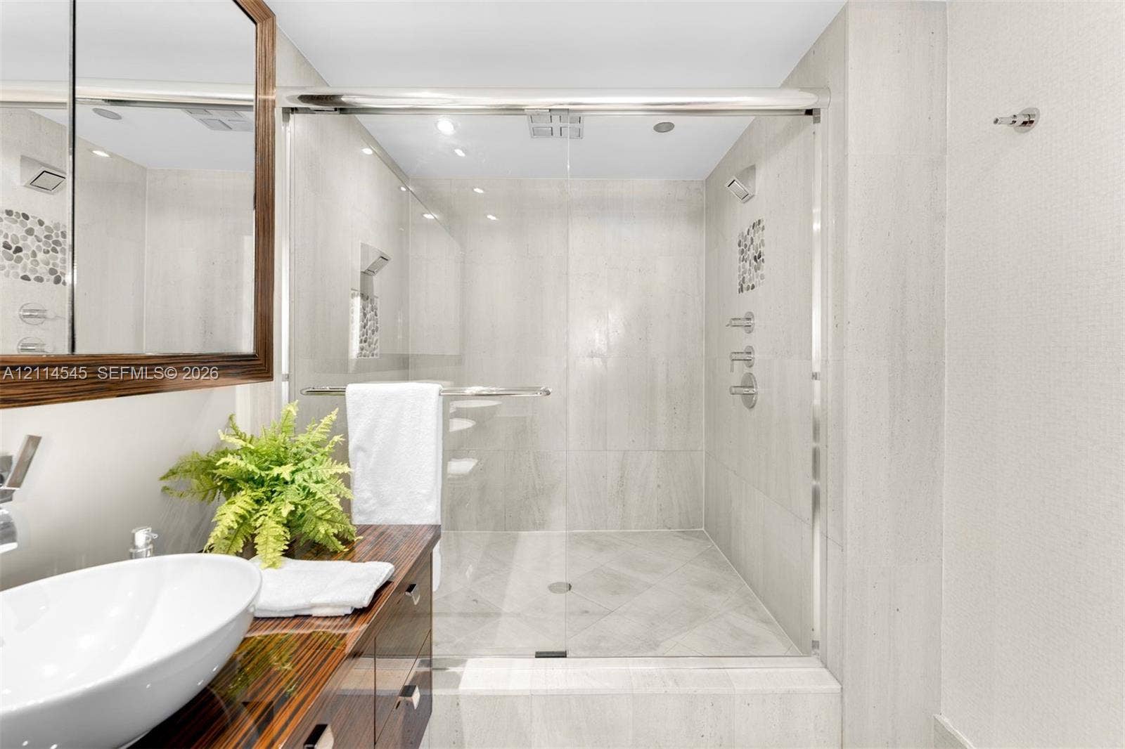 5875 Collins Avenue, #1503, Miami Beach, FL 33140 Walk-in shower featuring glass sliding doors, large-format tile surround, and mosaic tile accents