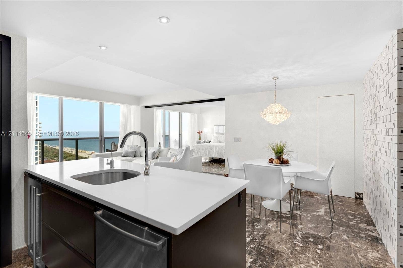 5875 Collins Avenue, #1503, Miami Beach, FL 33140 Kitchen island featuring a stone countertop, under-mount stainless steel sink, and sleek cabinetry